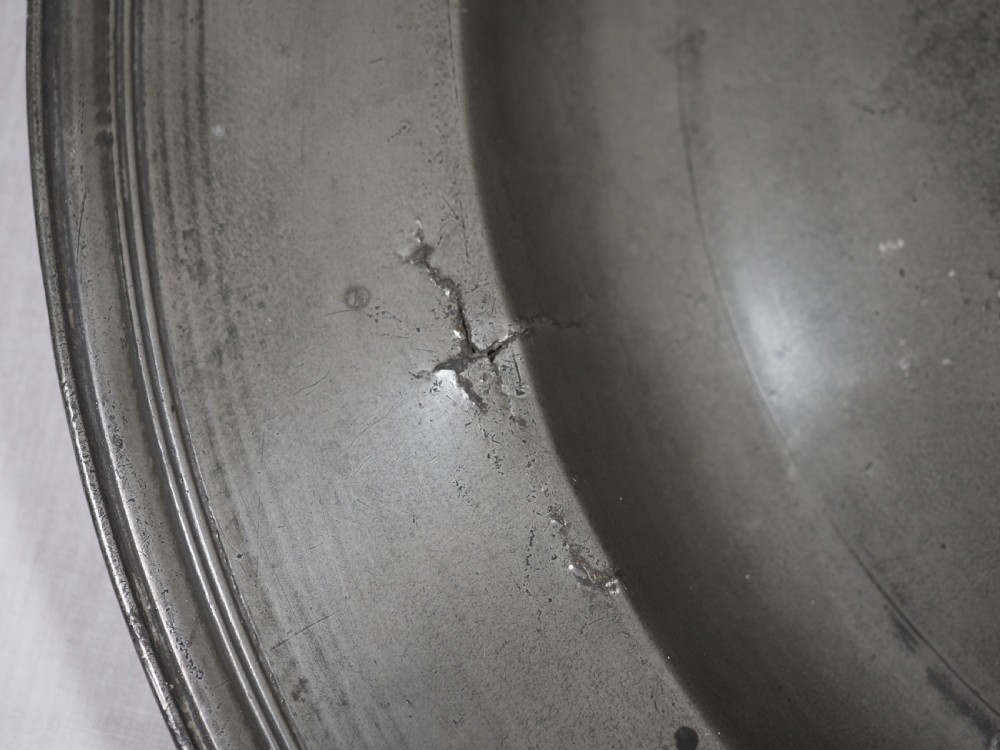 A circular 17th-century pewter charger plate featuring a wide rim decorated with triple reeded moulding and visible maker touchmarks. View VIII