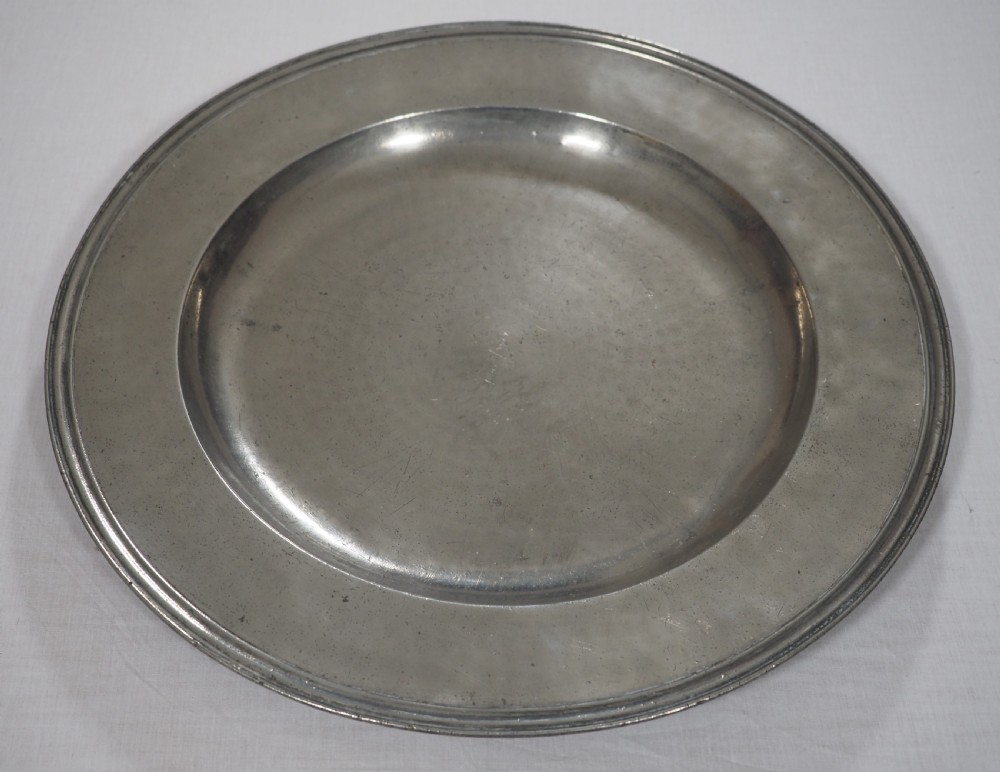 A circular late seventeenth-century grey pewter charger plate featuring a triple-reeded rim and hand-hammered surface finish. View II