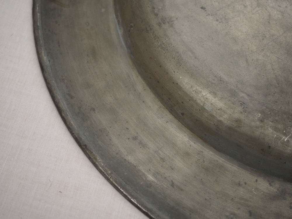 A circular late seventeenth-century grey pewter charger plate featuring a triple-reeded rim and hand-hammered surface finish. View VII