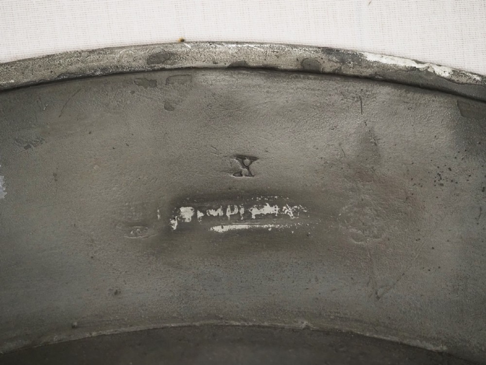 A circular seventeenth-century pewter charger plate with a plain rim featuring an engraved crest and stamped initials. View IX