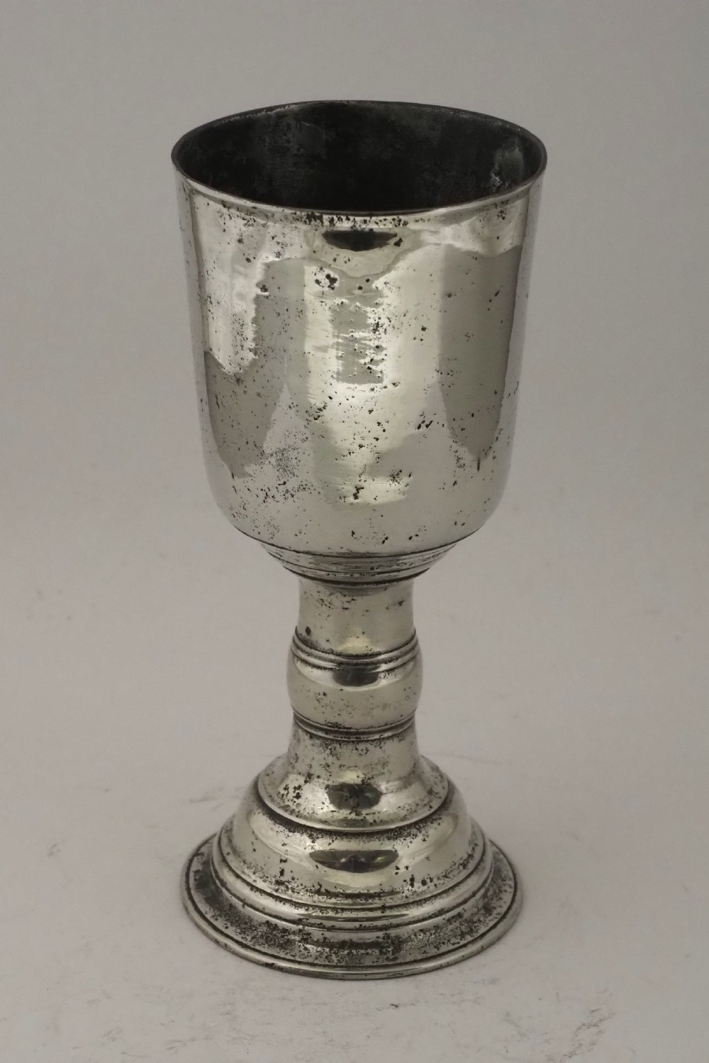 An antique Irish pewter chalice featuring a tall cylindrical bowl, a central knopped stem, and a stepped domed foot. View II
