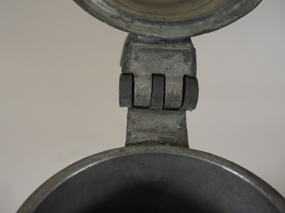 A dark grey early 18th-century English pewter spire flagon with a hinged lid, decorative spire finial, curved handle, and flared base. View VIII