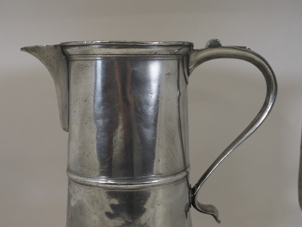 An 18th-century English pewter ale jug featuring a flared base, central girdle moulding, single poured spout, and curved handle. View II