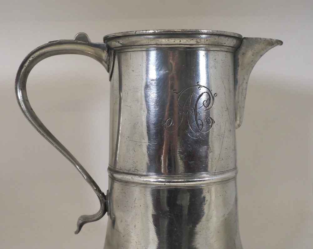 An 18th-century English pewter ale jug featuring a flared base, central girdle moulding, single poured spout, and curved handle. View V