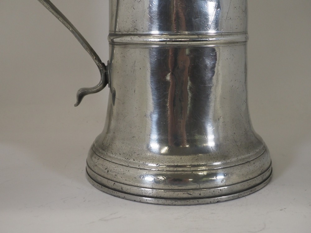An 18th-century English pewter ale jug featuring a flared base, central girdle moulding, single poured spout, and curved handle. View VI