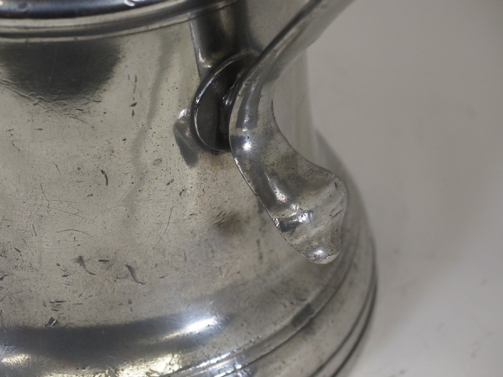 An 18th-century English pewter ale jug featuring a flared base, central girdle moulding, single poured spout, and curved handle. View XIII