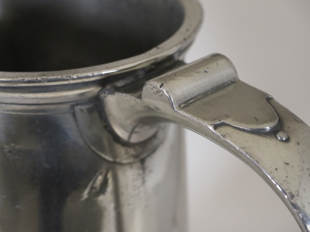 An 18th-century English pewter ale jug featuring a flared base, central girdle moulding, single poured spout, and curved handle. View XIV