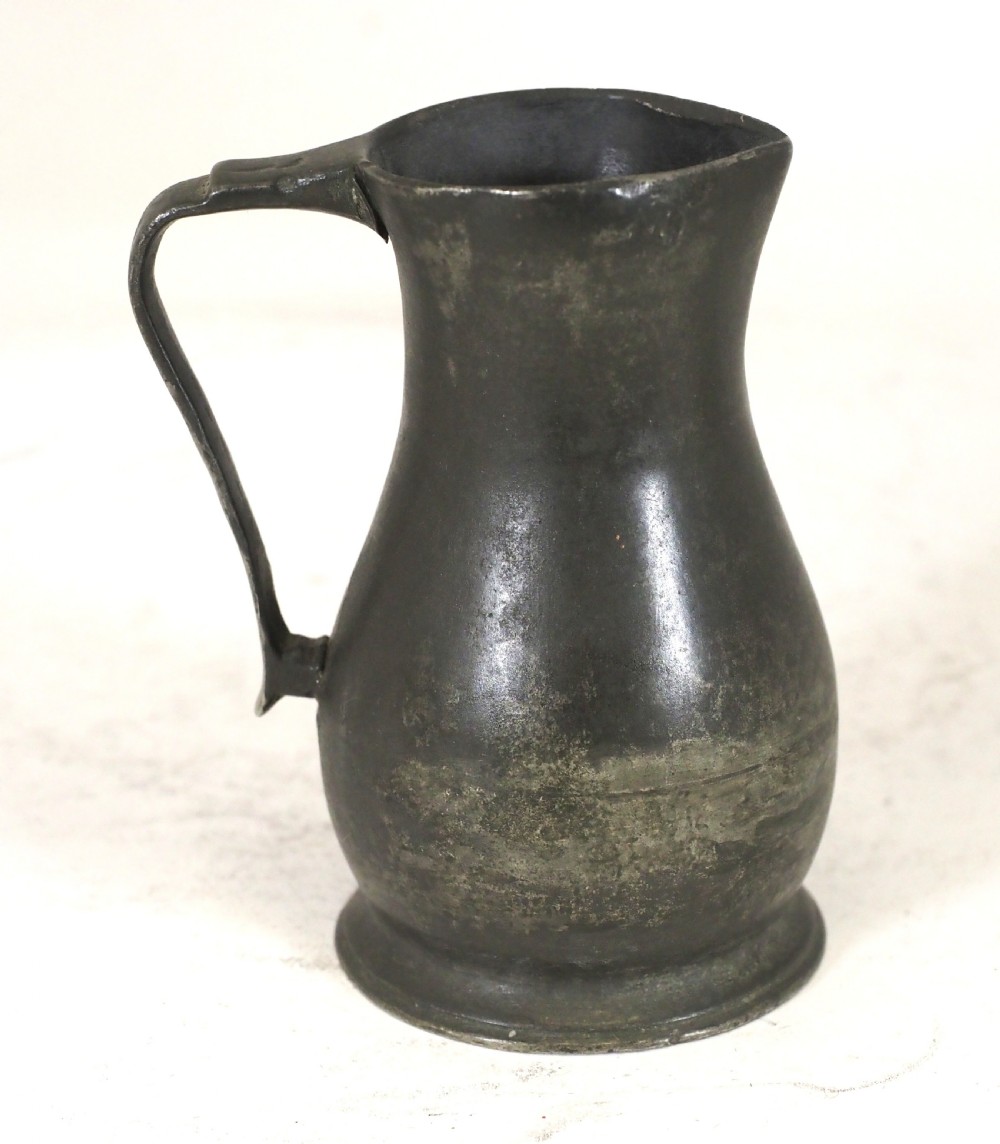 An antique dark grey pewter lidless baluster measure featuring a curved handle and flared rim. View III
