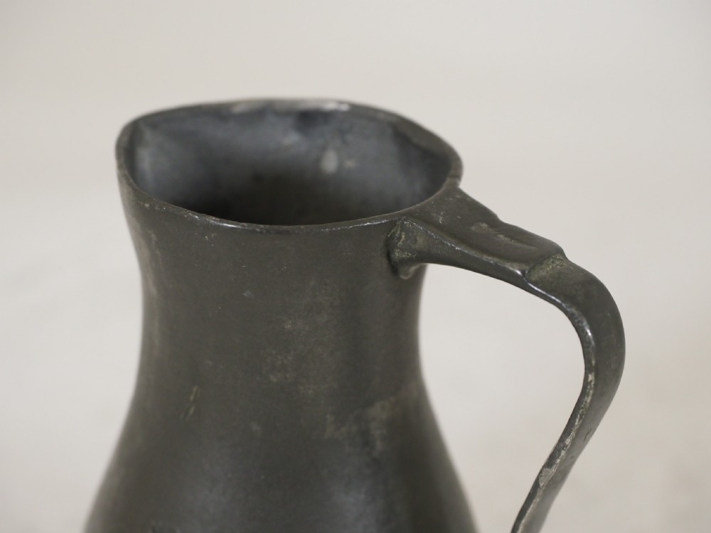 An antique dark grey pewter lidless baluster measure featuring a curved handle and flared rim. View V