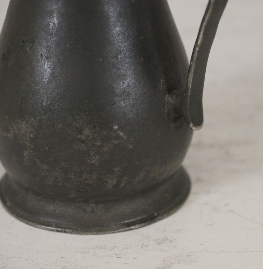 An antique dark grey pewter lidless baluster measure featuring a curved handle and flared rim. View VI
