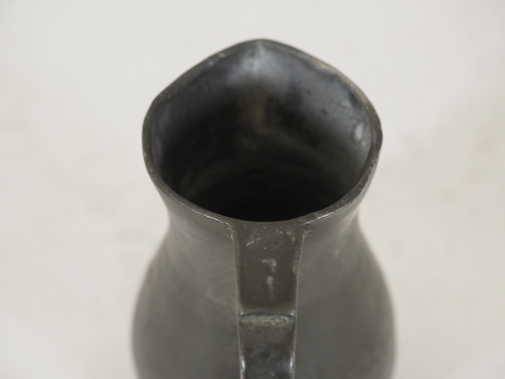 An antique dark grey pewter lidless baluster measure featuring a curved handle and flared rim. View VII