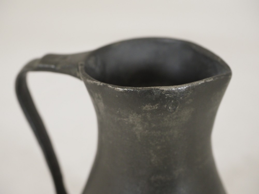 An antique dark grey pewter lidless baluster measure featuring a curved handle and flared rim. View VIII