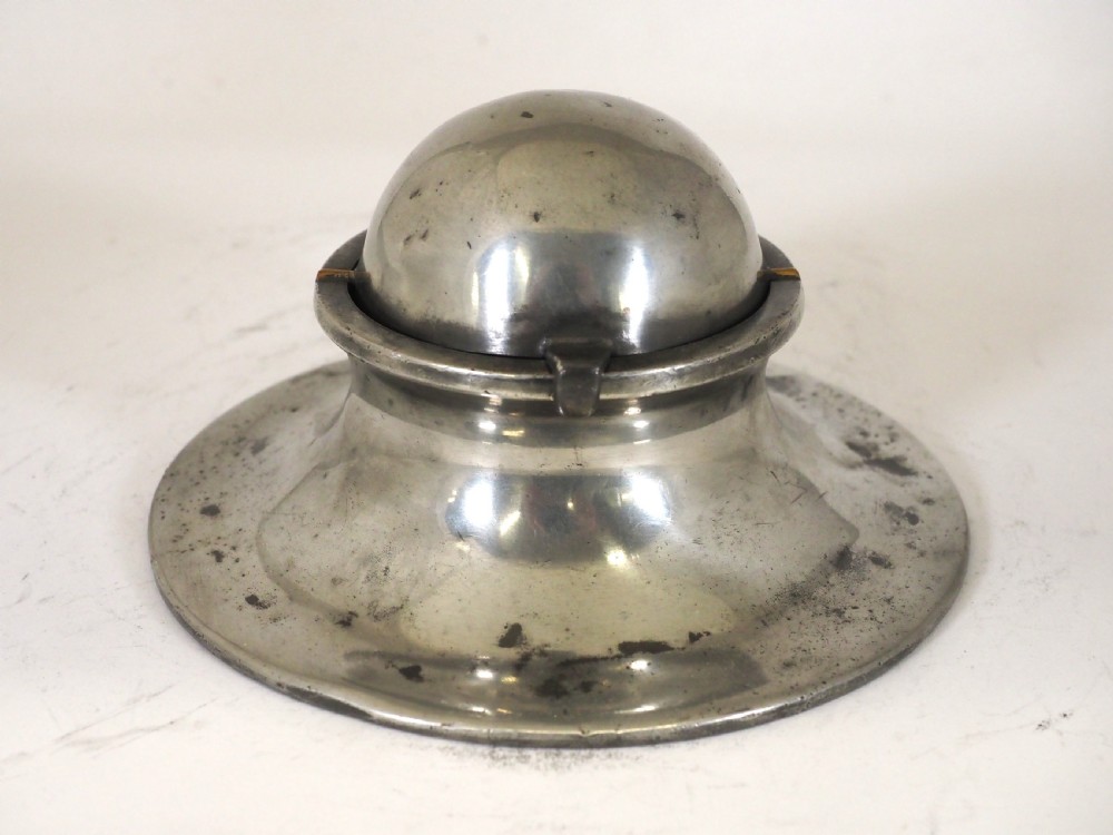 An antique pewter ships inkwell featuring a wide circular capstan base and a domed lid.