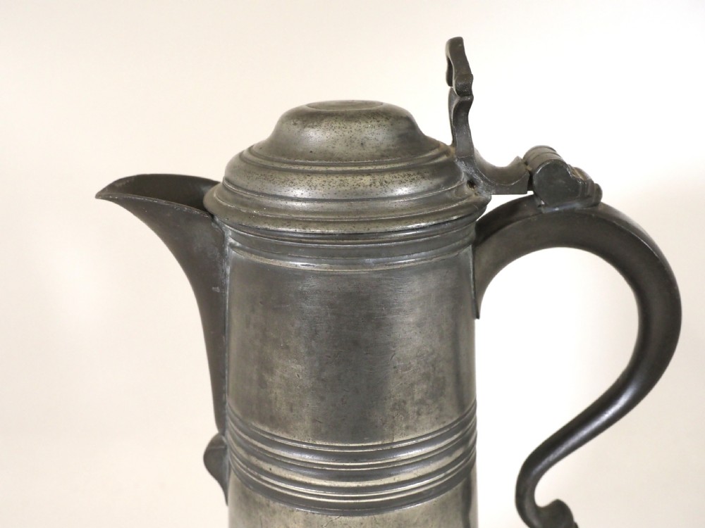 An antique late 18th-century spouted pewter spire flagon featuring a double-scroll handle, domed lid, and flared circular base. View II