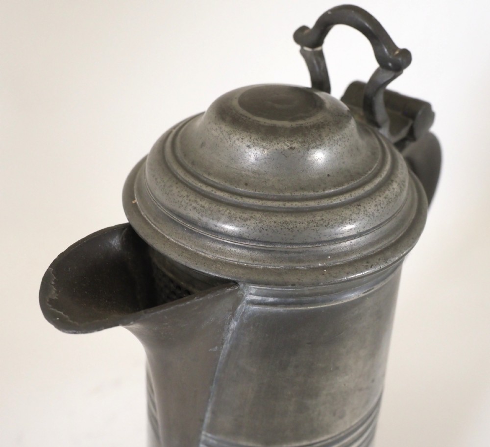 An antique late 18th-century spouted pewter spire flagon featuring a double-scroll handle, domed lid, and flared circular base. View VIII