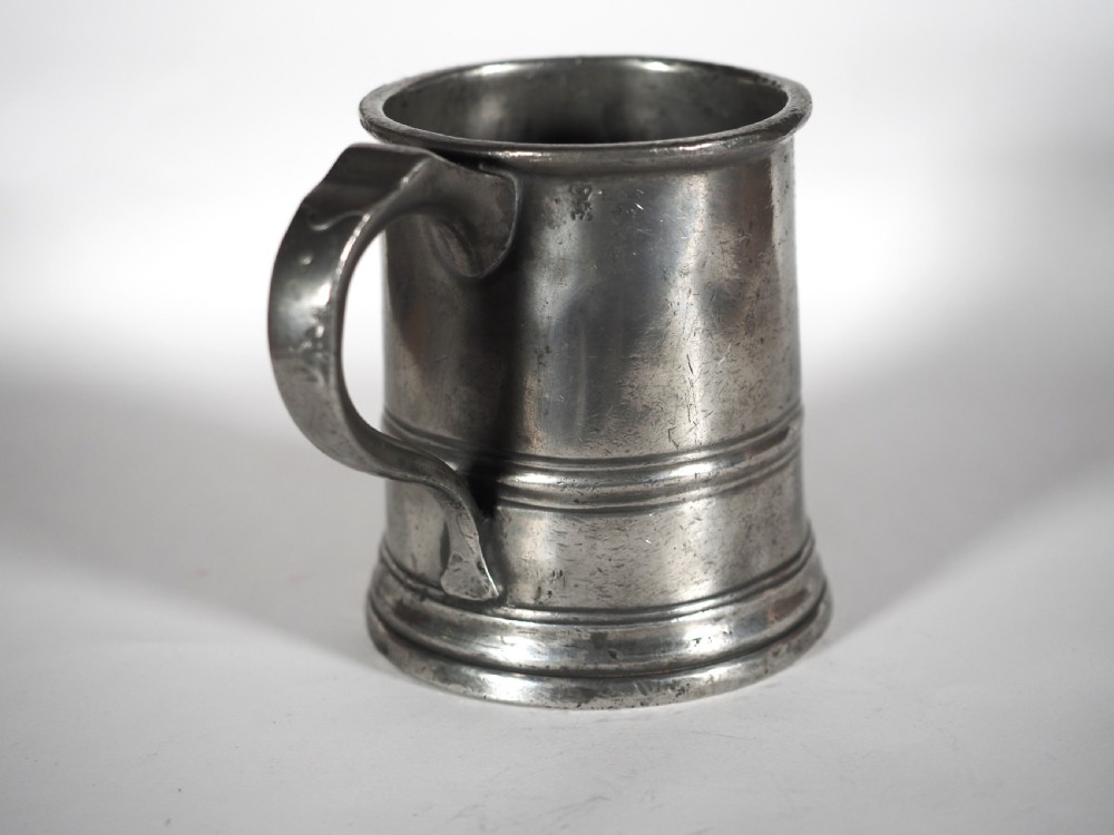 An antique grey pewter pint measure featuring a curved handle, cylindrical body with moulded bands, and engraved lettering on the side. View III