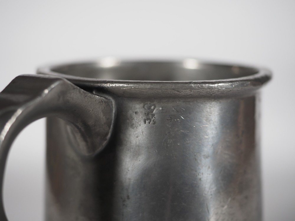 An antique grey pewter pint measure featuring a curved handle, cylindrical body with moulded bands, and engraved lettering on the side. View VI