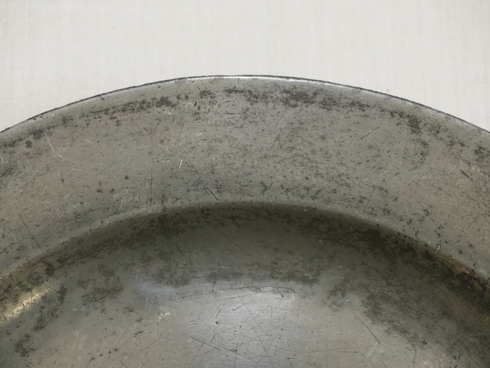 An 18th-century circular English pewter plate featuring a wide plain rim and aged grey metal patination. View III