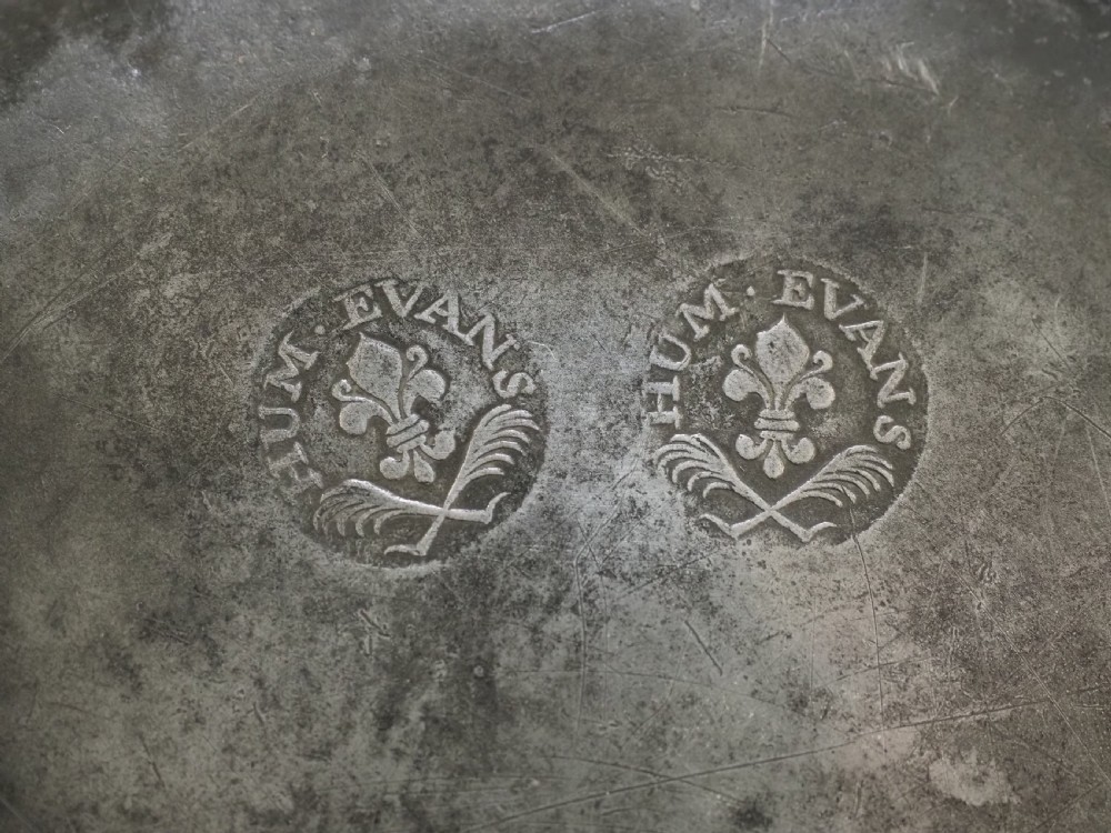 An 18th-century circular English pewter plate featuring a wide plain rim and aged grey metal patination. View V