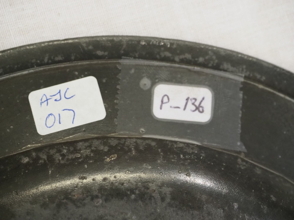 An 18th-century circular English pewter plate featuring a wide plain rim and aged grey metal patination. View VII