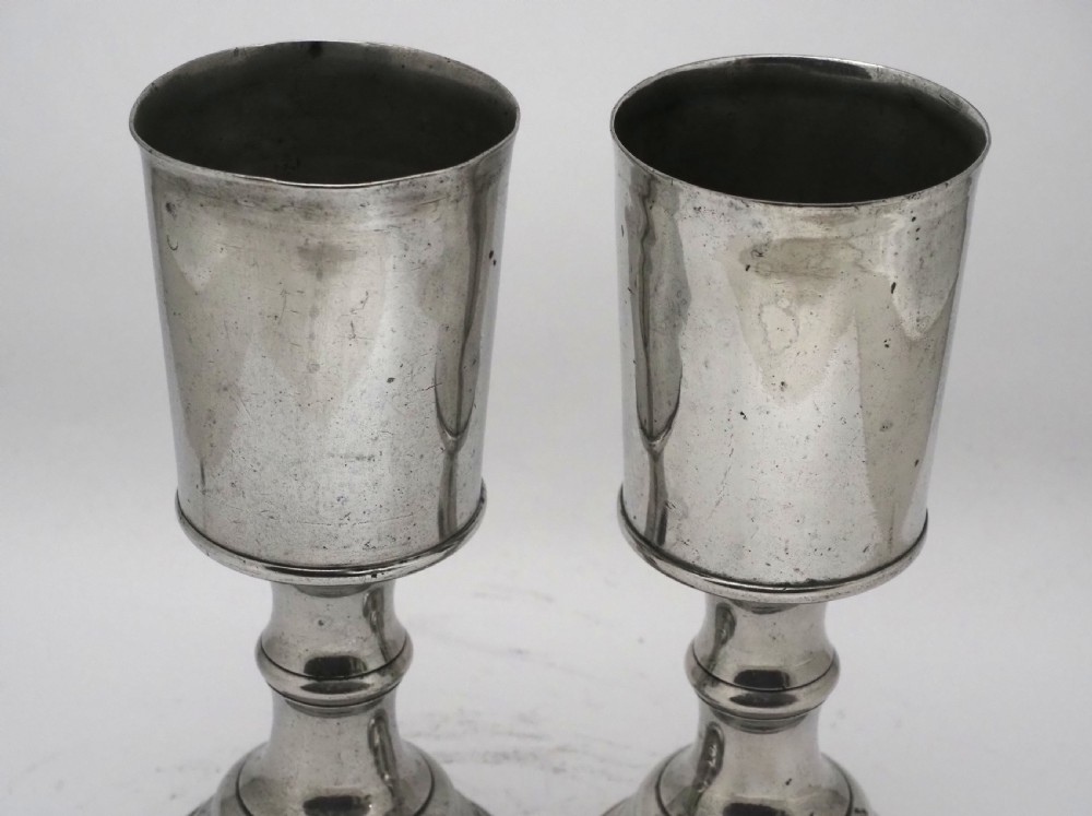 A pair of Georgian pewter chalices featuring cylindrical bowls, knopped stems, and stepped circular bases. View IV