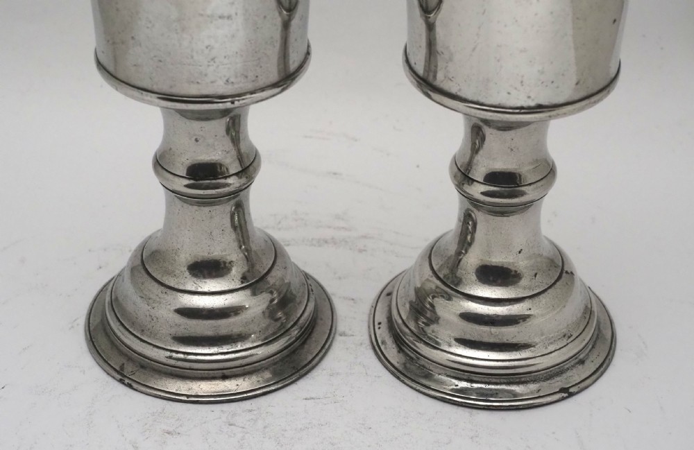 A pair of Georgian pewter chalices featuring cylindrical bowls, knopped stems, and stepped circular bases. View V