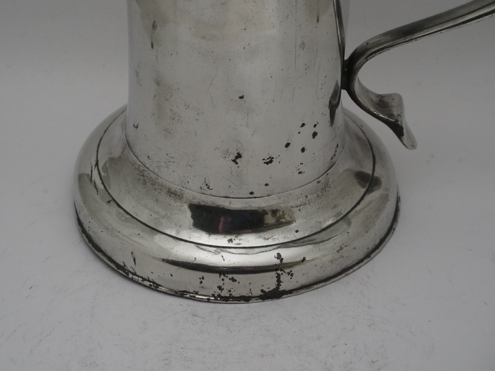 An 18th-century Irish pewter church flagon with a domed hinged lid, thumbpiece, curved handle, and broad flared base. View II