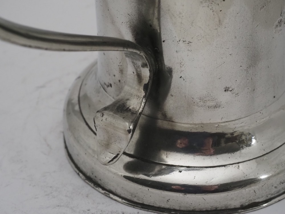 An 18th-century Irish pewter church flagon with a domed hinged lid, thumbpiece, curved handle, and broad flared base. View III