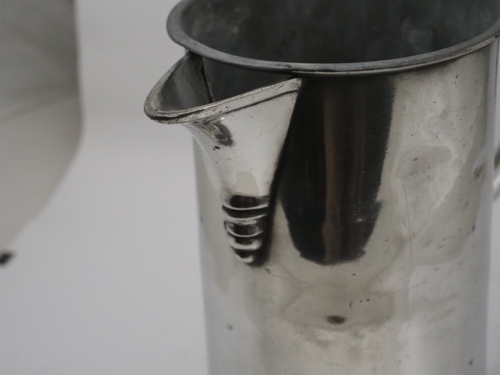 An 18th-century Irish pewter church flagon with a domed hinged lid, thumbpiece, curved handle, and broad flared base. View VII
