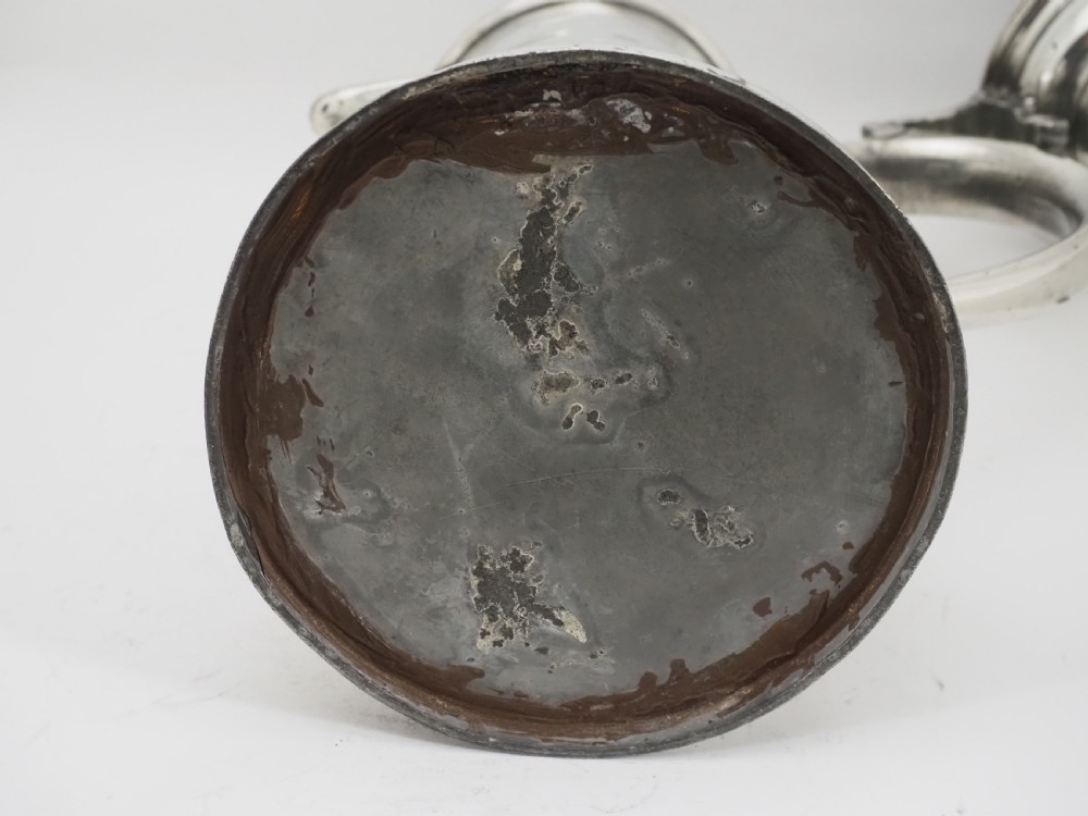 An 18th-century Irish pewter church flagon with a domed hinged lid, thumbpiece, curved handle, and broad flared base. View IX