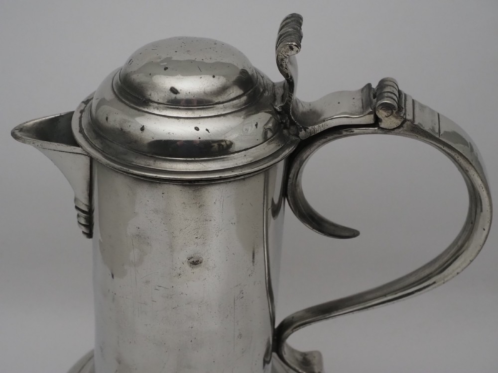 An 18th-century Irish pewter church flagon with a domed hinged lid, thumbpiece, curved handle, and broad flared base. View XI