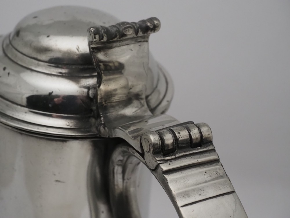 An 18th-century Irish pewter church flagon with a domed hinged lid, thumbpiece, curved handle, and broad flared base. View XIII