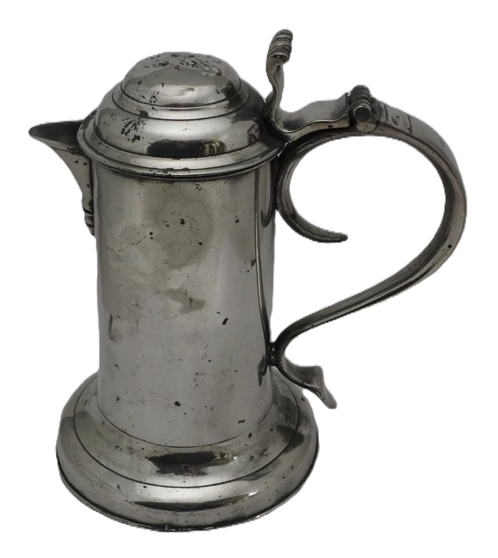 An 18th-century Georgian Irish pewter church flagon featuring a domed hinged lid, double-scroll handle, spout, and circular moulded base.