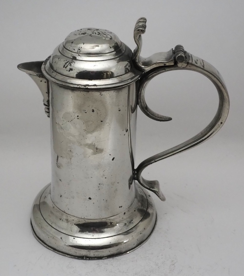 An 18th-century Georgian Irish pewter church flagon featuring a domed hinged lid, double-scroll handle, spout, and circular moulded base. View II