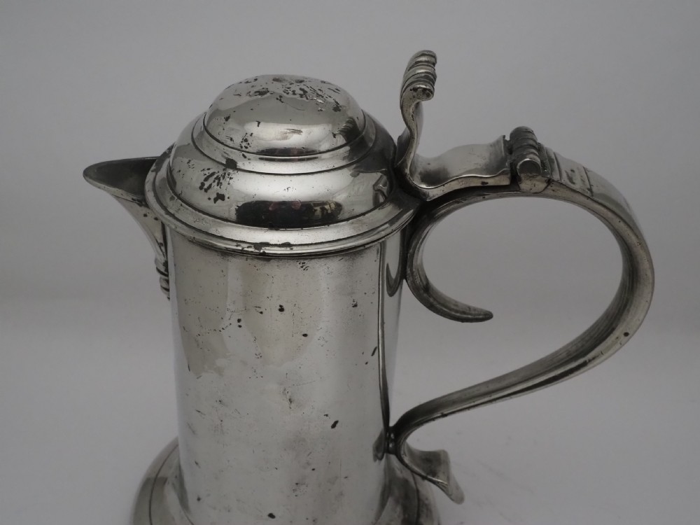 An 18th-century Georgian Irish pewter church flagon featuring a domed hinged lid, double-scroll handle, spout, and circular moulded base. View IV
