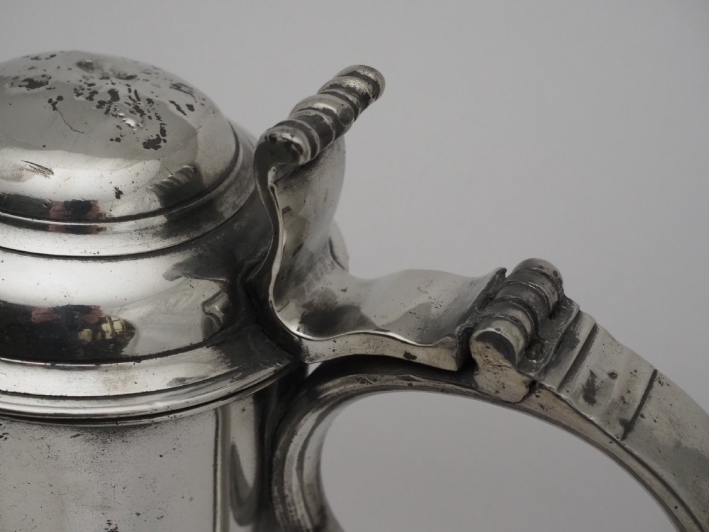 An 18th-century Georgian Irish pewter church flagon featuring a domed hinged lid, double-scroll handle, spout, and circular moulded base. View V