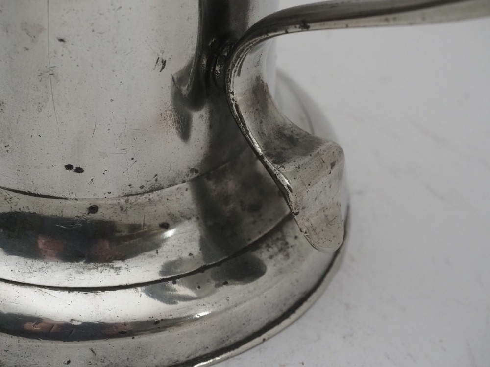 An 18th-century Georgian Irish pewter church flagon featuring a domed hinged lid, double-scroll handle, spout, and circular moulded base. View VI