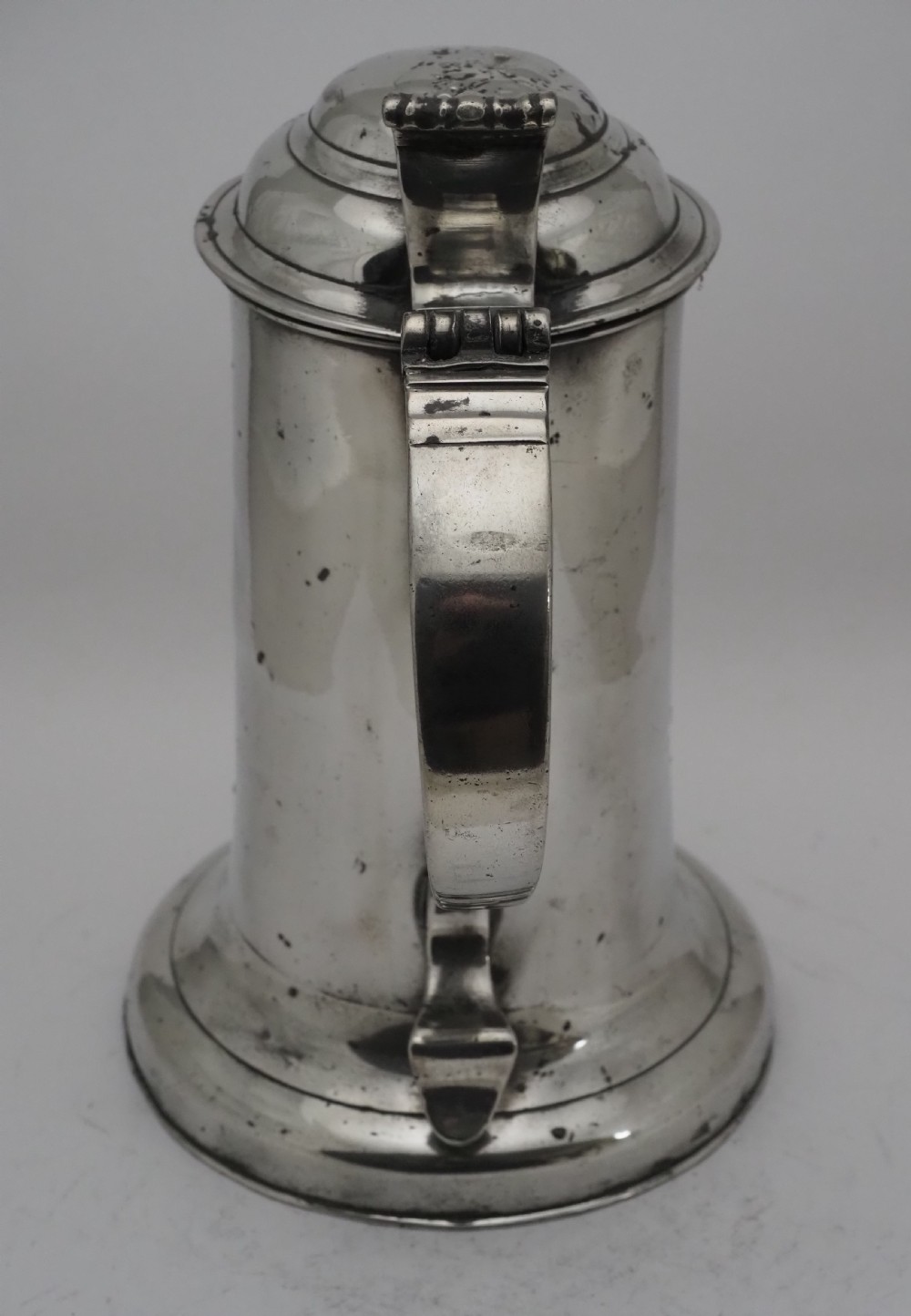 An 18th-century Georgian Irish pewter church flagon featuring a domed hinged lid, double-scroll handle, spout, and circular moulded base. View VIII