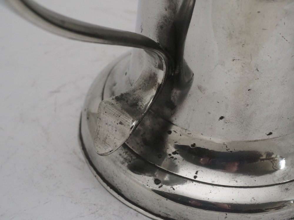 An 18th-century Georgian Irish pewter church flagon featuring a domed hinged lid, double-scroll handle, spout, and circular moulded base. View X