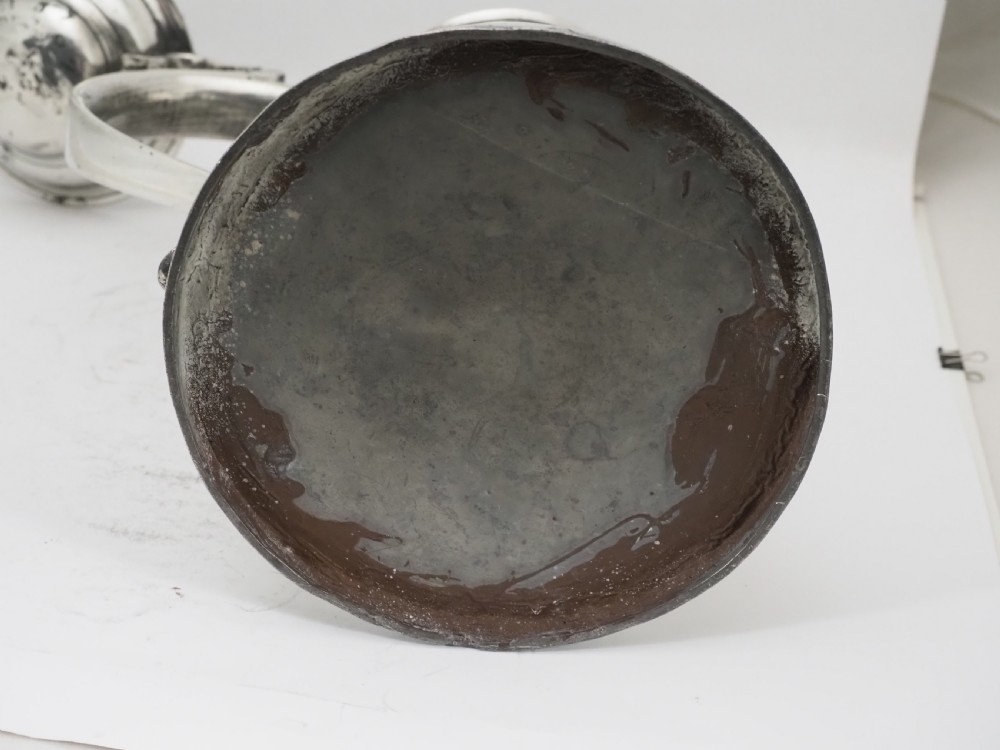 An 18th-century Georgian Irish pewter church flagon featuring a domed hinged lid, double-scroll handle, spout, and circular moulded base. View XV