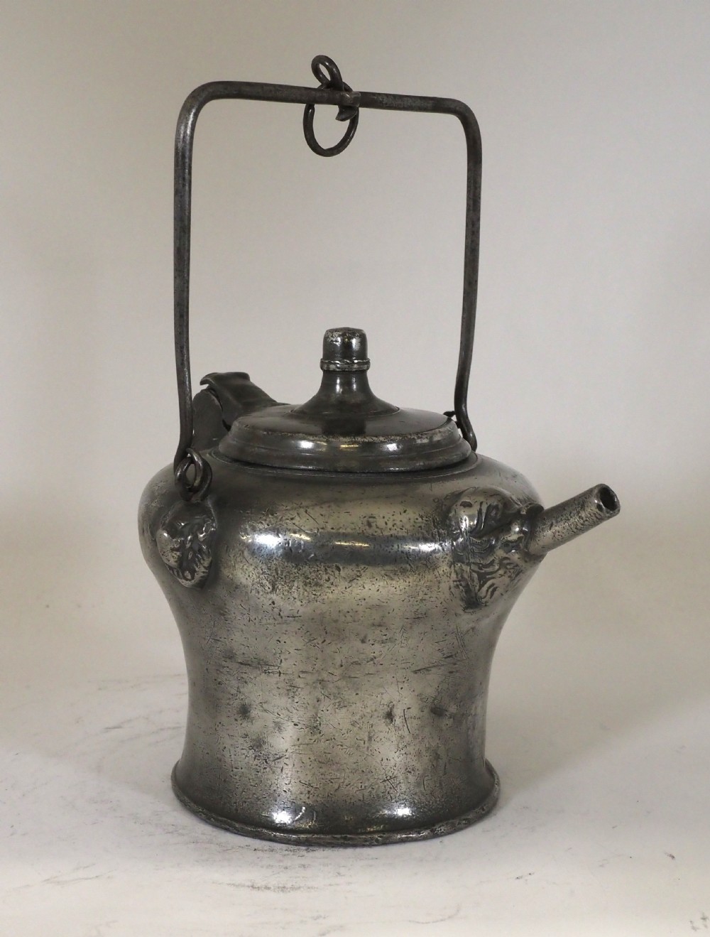 An antique 18th-century Swiss pewter biberon water vessel featuring a flared base, side spout with relief detailing, fitted lid, and tall wire handle. View II