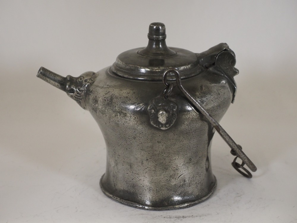 An antique 18th-century Swiss pewter biberon water vessel featuring a flared base, side spout with relief detailing, fitted lid, and tall wire handle. View III