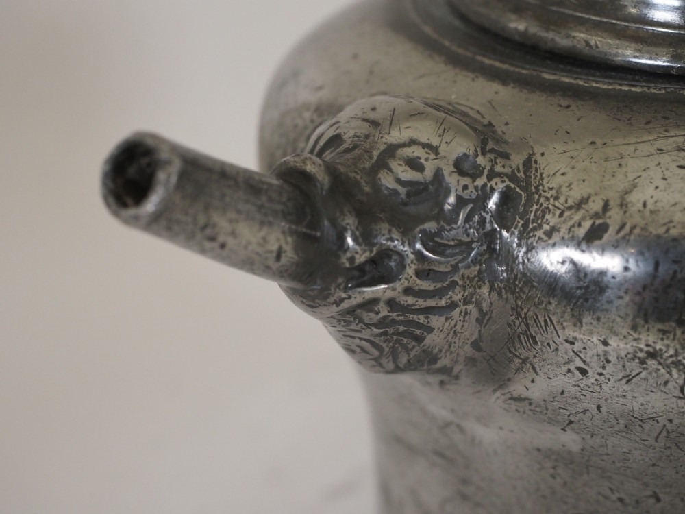An antique 18th-century Swiss pewter biberon water vessel featuring a flared base, side spout with relief detailing, fitted lid, and tall wire handle. View V