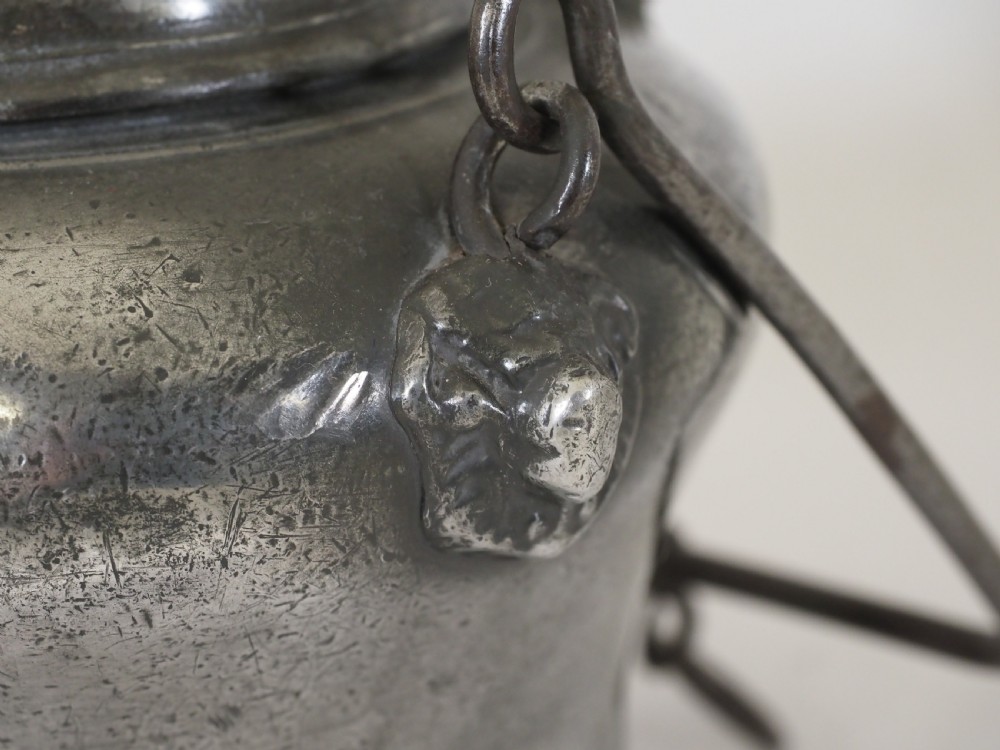An antique 18th-century Swiss pewter biberon water vessel featuring a flared base, side spout with relief detailing, fitted lid, and tall wire handle. View VII