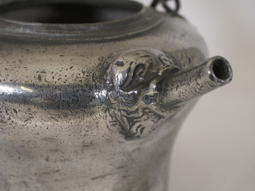 An antique 18th-century Swiss pewter biberon water vessel featuring a flared base, side spout with relief detailing, fitted lid, and tall wire handle. View IX