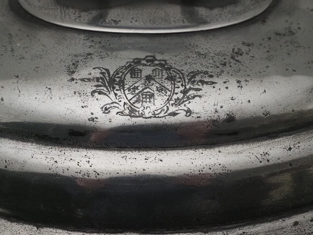 An antique Georgian pewter oval soup tureen featuring a domed lid with a loop handle, twin side handles, cabriole legs, and an engraved armorial crest. View V
