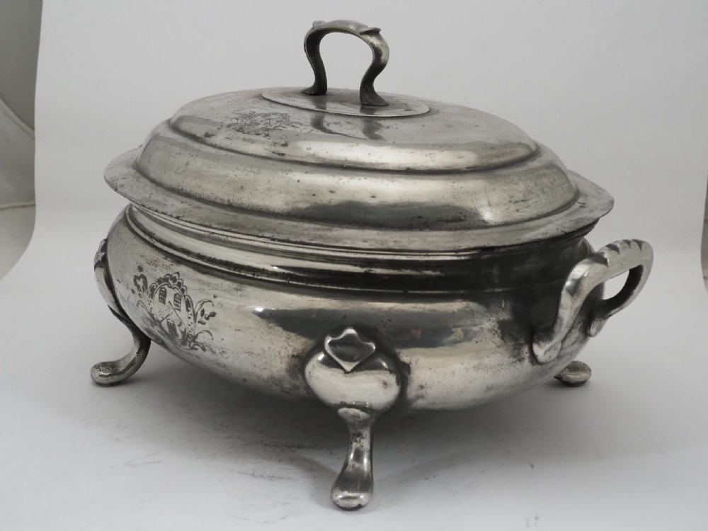 An antique Georgian pewter oval soup tureen featuring a domed lid with a loop handle, twin side handles, cabriole legs, and an engraved armorial crest. View VIII