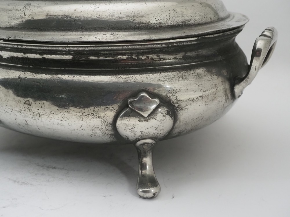 An antique Georgian pewter oval soup tureen featuring a domed lid with a loop handle, twin side handles, cabriole legs, and an engraved armorial crest. View XI
