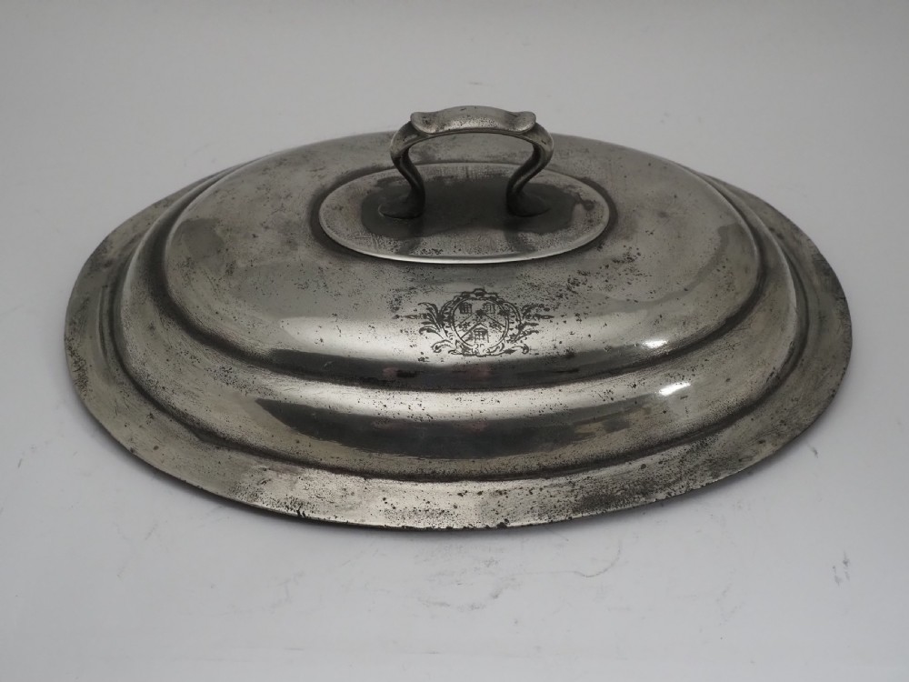 An antique Georgian pewter oval soup tureen featuring a domed lid with a loop handle, twin side handles, cabriole legs, and an engraved armorial crest. View XIV