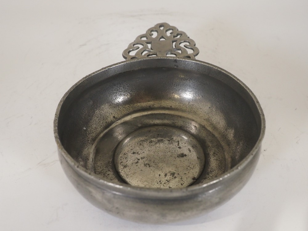 An antique silver-grey pewter porringer bowl featuring a single ornate pierced scrollwork ear handle. View III